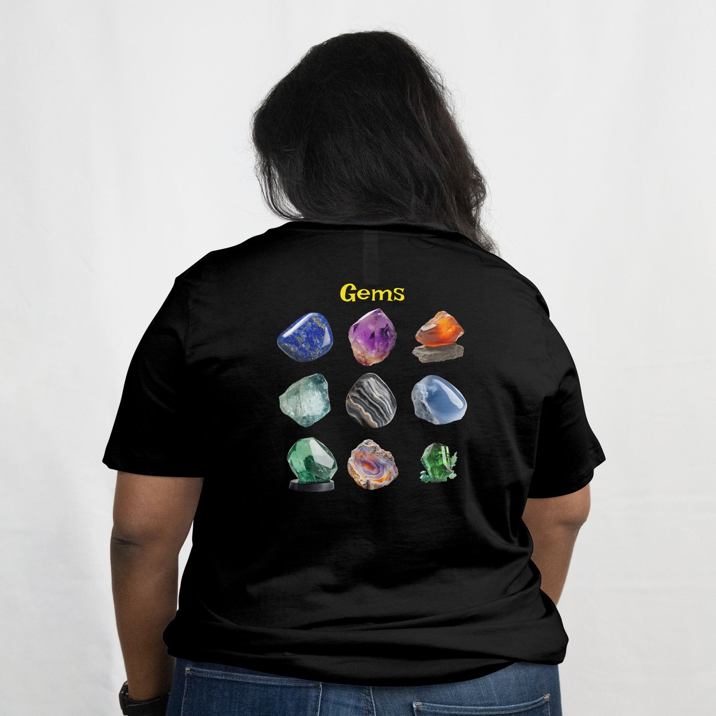 Person wearing a black t-shirt with a collection of various colorful crystals on a white background with 'Gems' text on the top. The graphic is on the back.