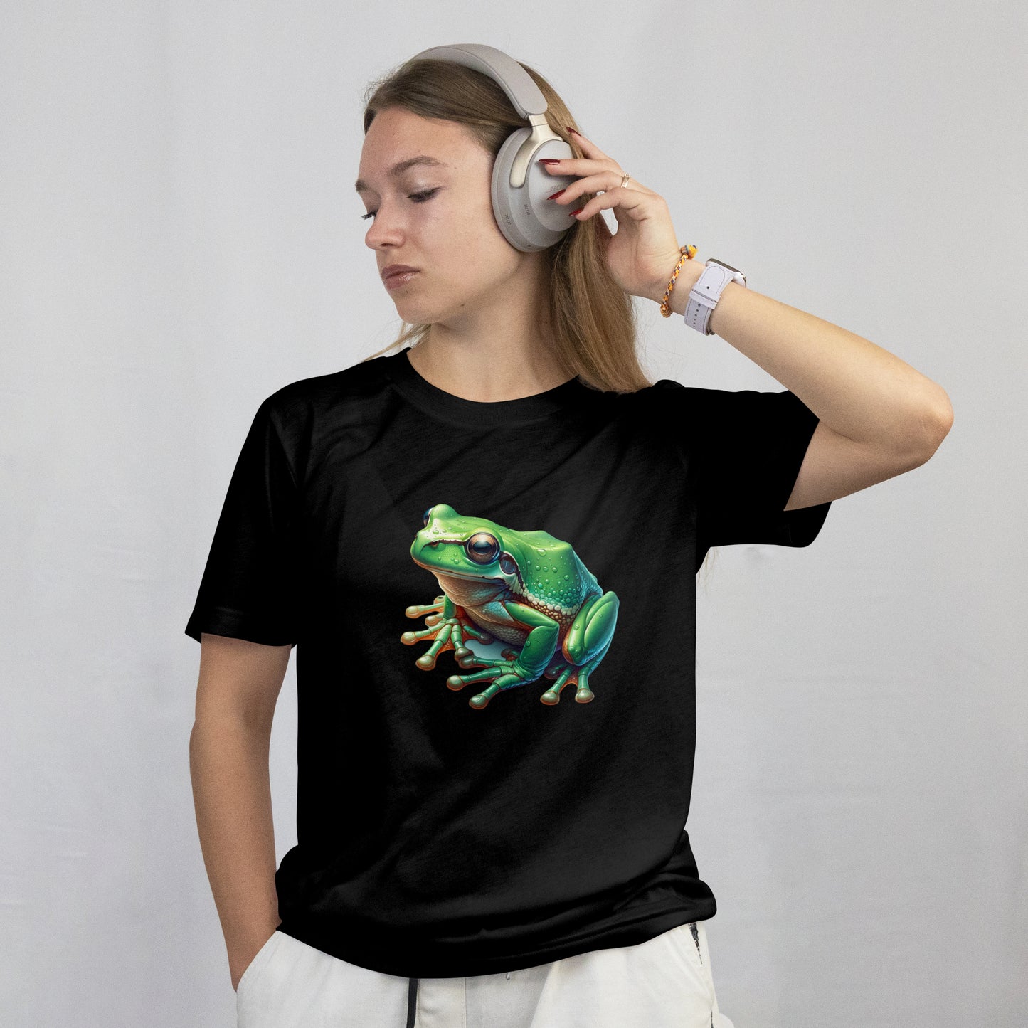 Person wearing a black t-shirt with a green frog graphic and headphones, on a plain background
