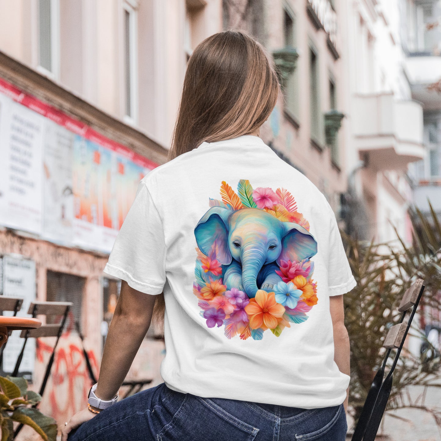 Person wearing a white t-shirt with a colorful elephant design outdoors.