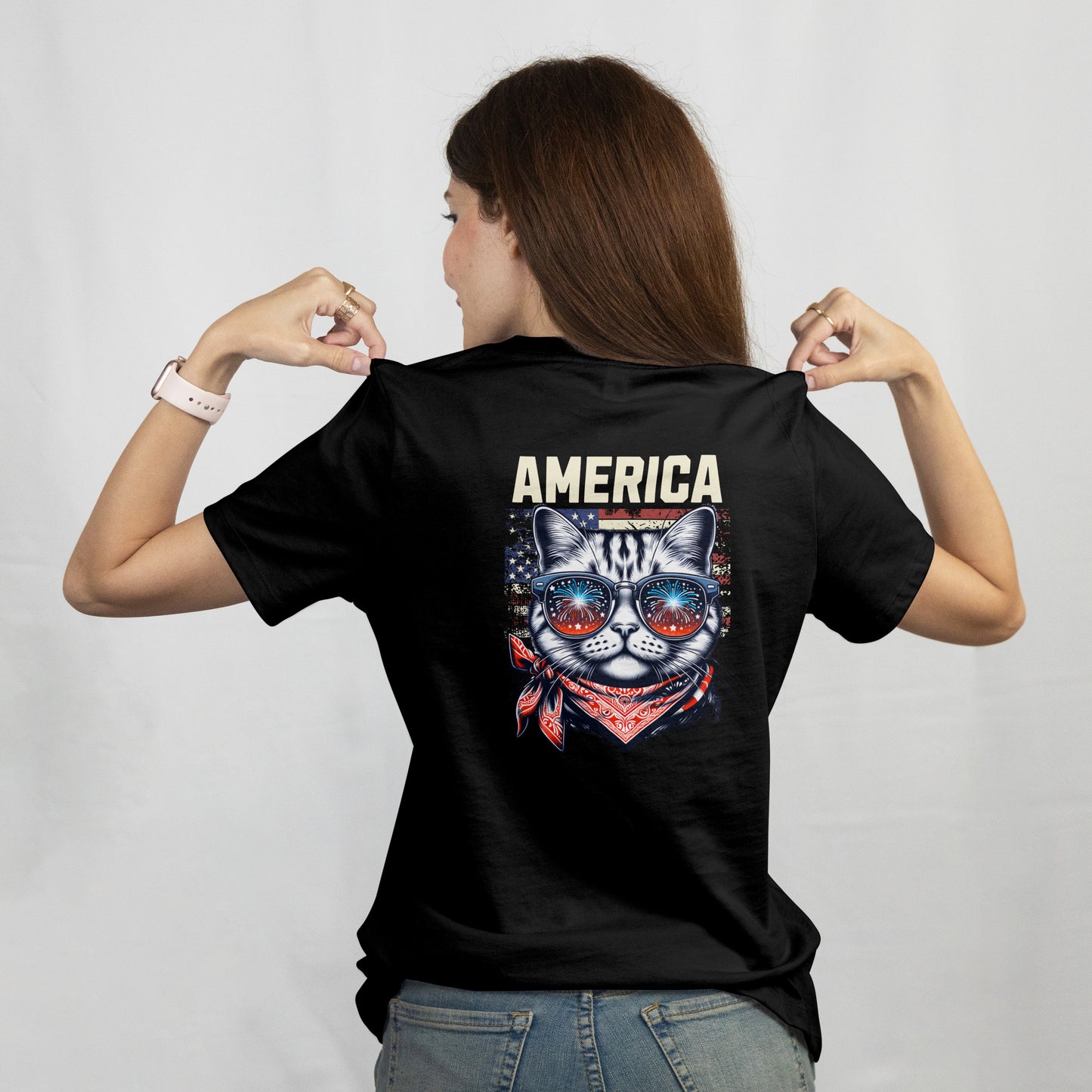 Person wearing a black t-shirt with a cat wearing American flag sunglasses and bandana on a black background on the back.