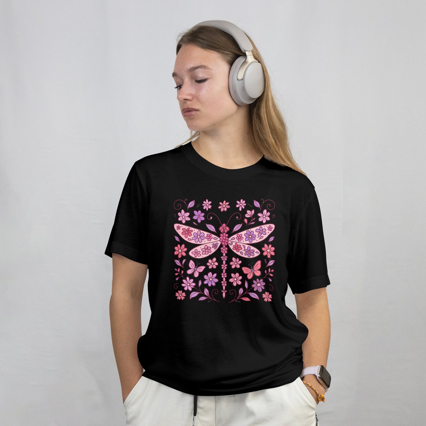 Person wearing a black t-shirt with a decorative design with pink dragonfly and flowers on a black background