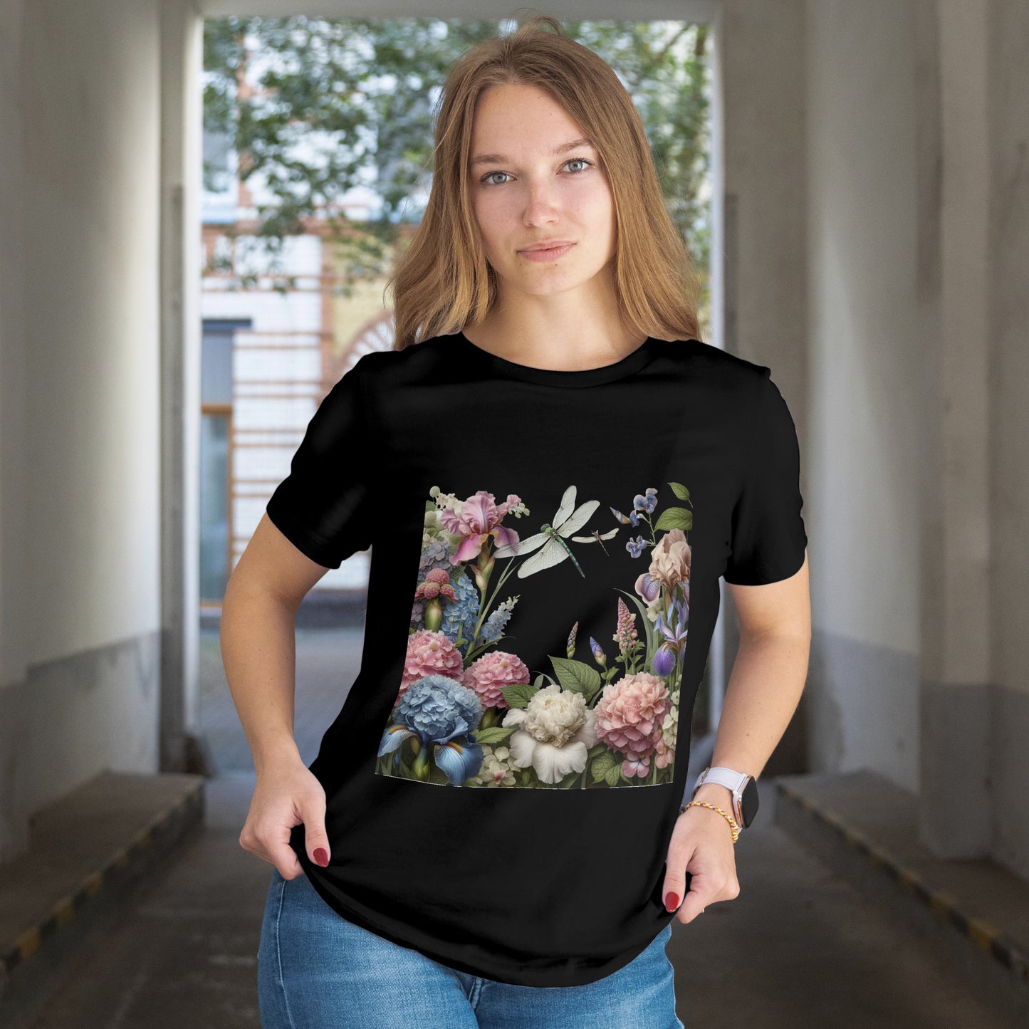 Person wearing a black t-shirt with Illustration of flowers and dragonflies on a black background. The model is in an indoor setting