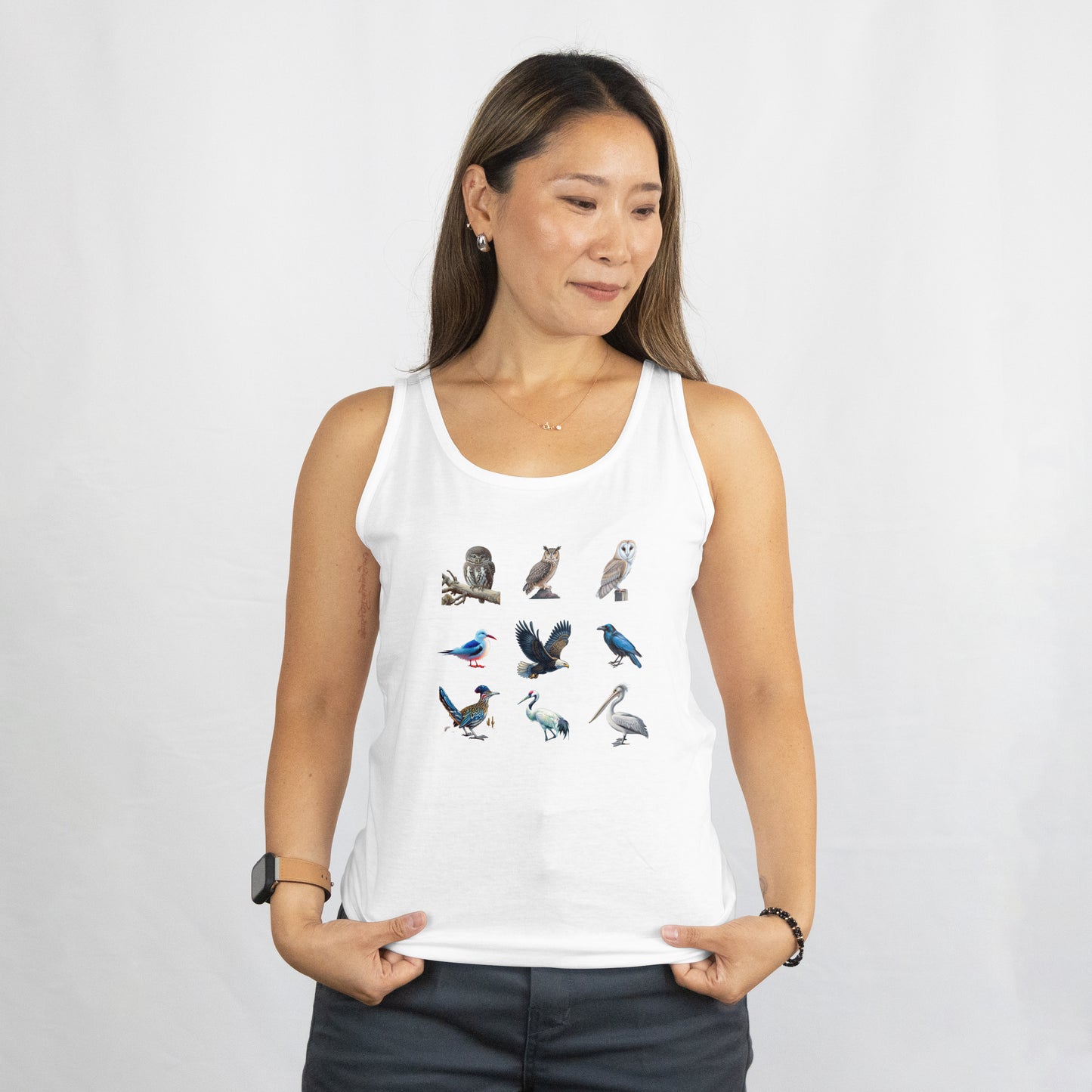 A woman wearing a white tank top featuring illustrations of various birds, including an owl, eagle, and pelican, displayed on a plain background.