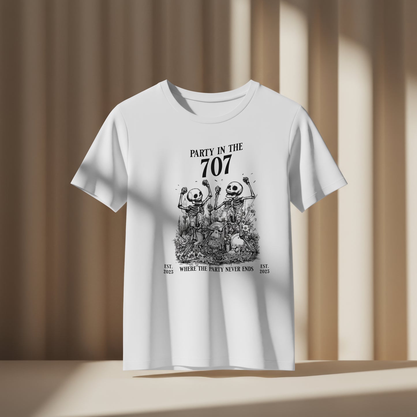 White t-shirt with two skeletons celebrating with text 'Party in the 707' and 'Where the party never ends' on a white background. The shirt is against a beige background