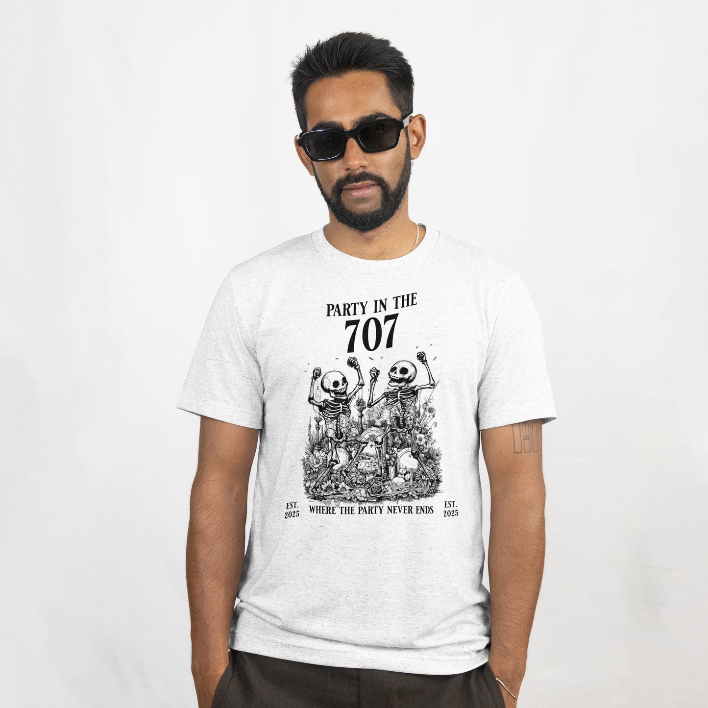 Man wearing a white t-shirt with two skeletons celebrating with text 'Party in the 707' and 'Where the party never ends' on a white background. The model is standing against a plain background