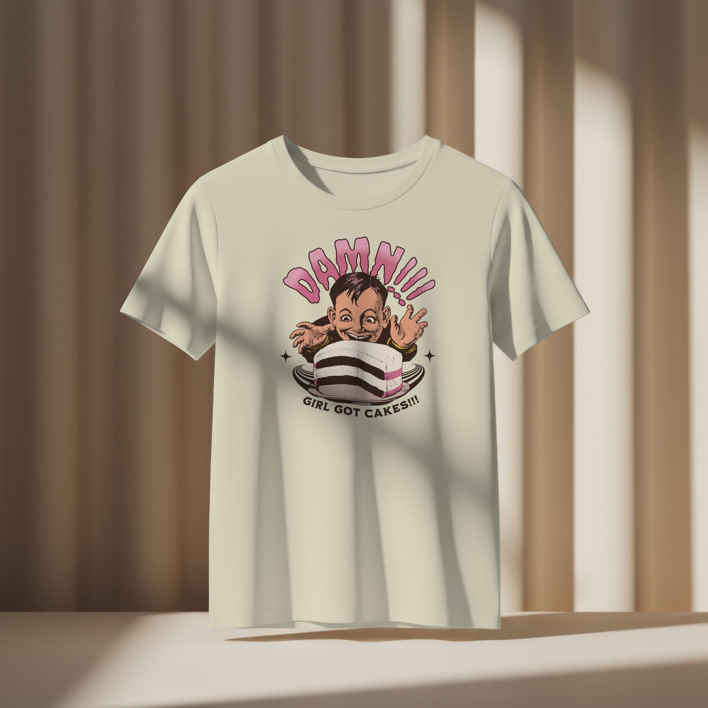 White t-shirt with cartoon character with a cake and text 'Damn!!! Girl Got Cakes!!!' on a white background. the shirt is displayed on a neutral background