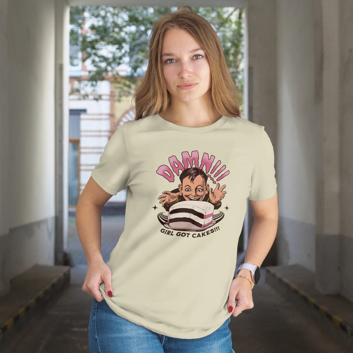 Woman wearing a t-shirt with a cartoon character with a cake and text 'Damn!!! Girl Got Cakes!!!' on a white background.