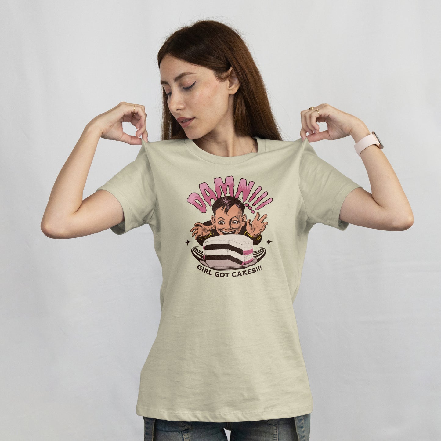 Woman wearing a t shirt with a cartoon character with a cake and text 'Damn!!! Girl Got Cakes!!!' on a white background.