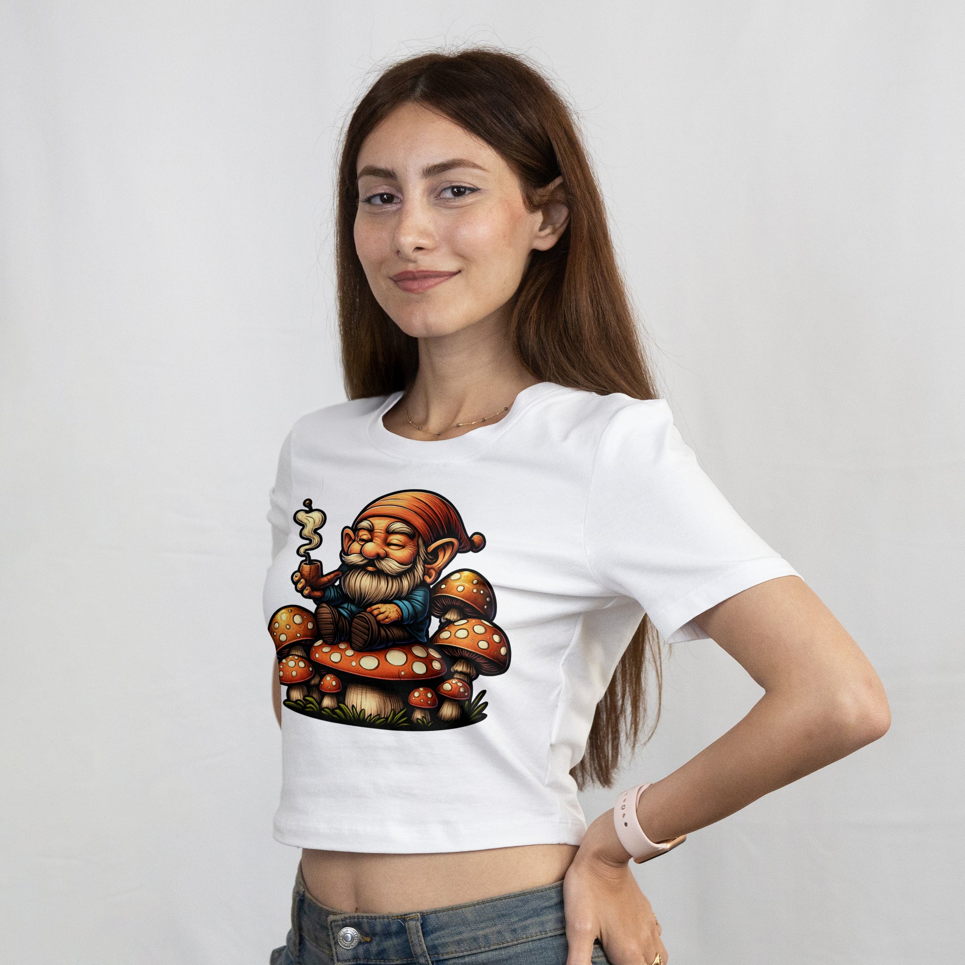Woman wearing a white t-shirt with a Cartoon gnome sitting on mushrooms with a smoking pipe on a plain background
