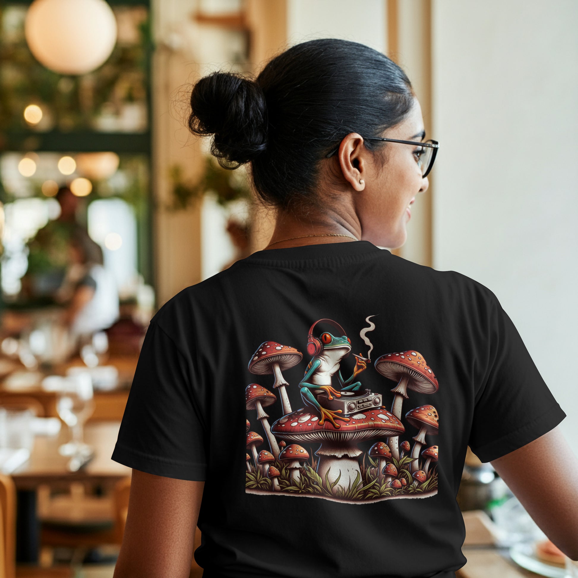Person wearing a black t-shirt with a frog with headphones smoking a cigarette on a mushroom, surrounded by more mushrooms, in a restaurant setting