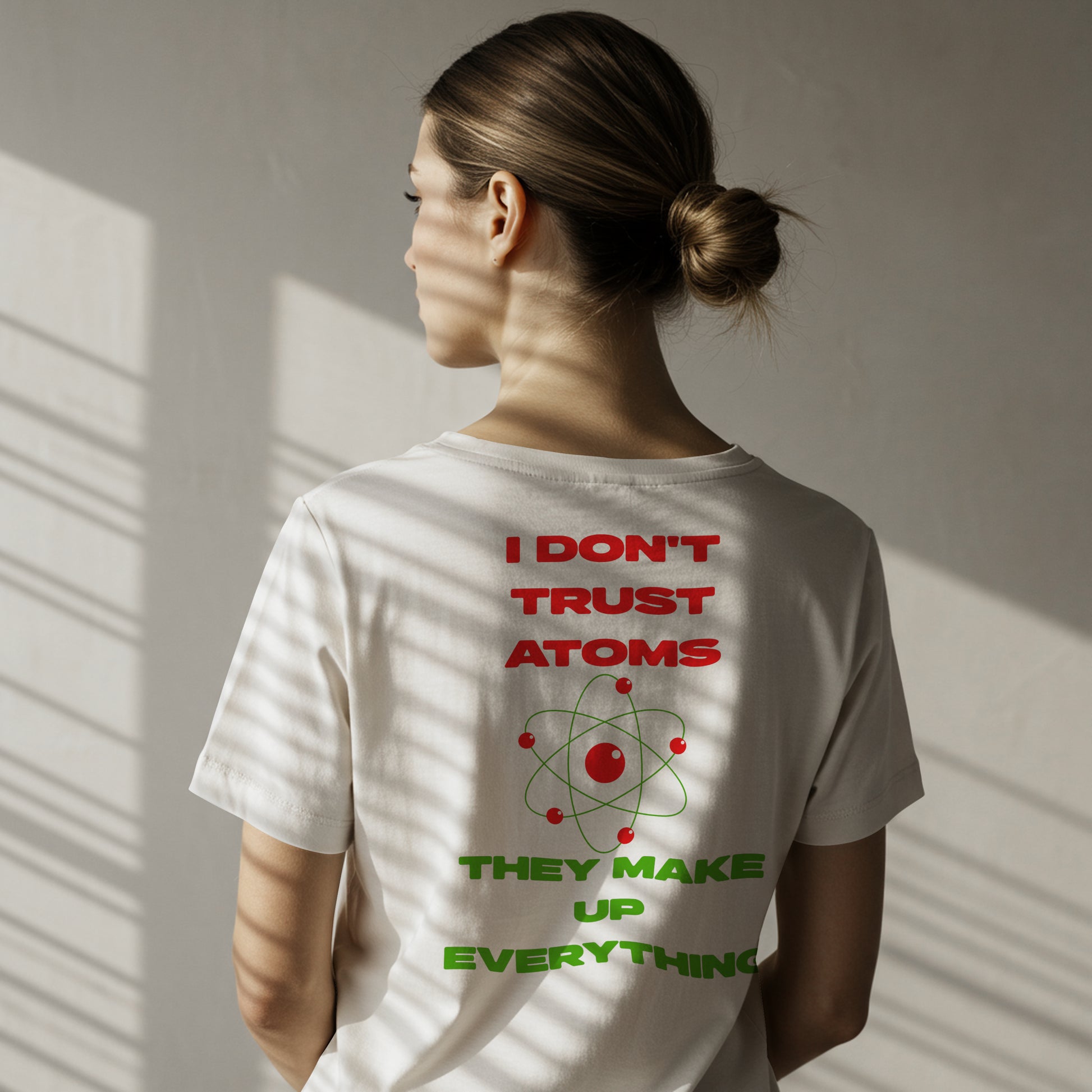 Female wearing a white t-shirt with "I don't trust atoms, they make up everything." A red atom symbol on a white background is in the center of the text