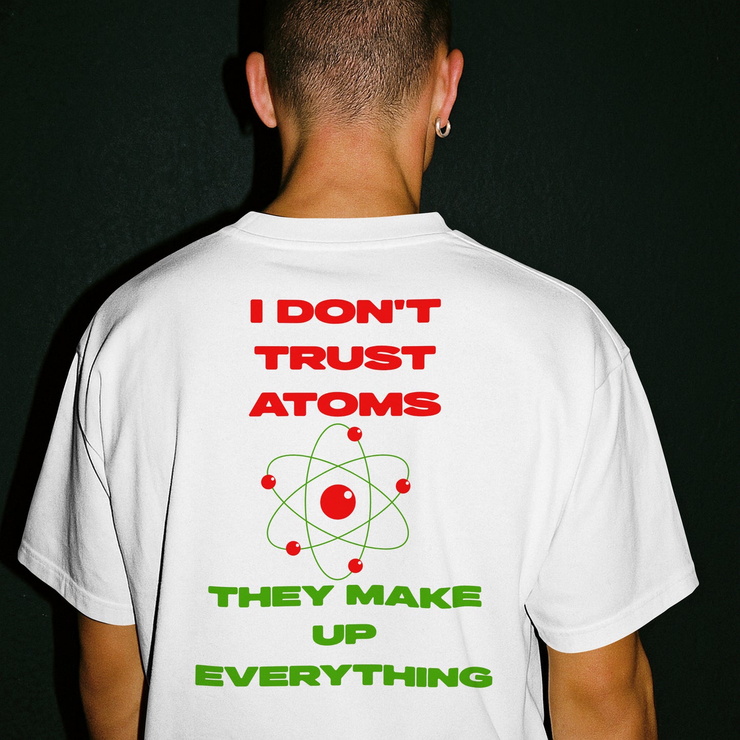 A male wearing a white t-shirt with "I don't trust atoms, they make up everything." A red atom symbol on a white background is in the center of the text