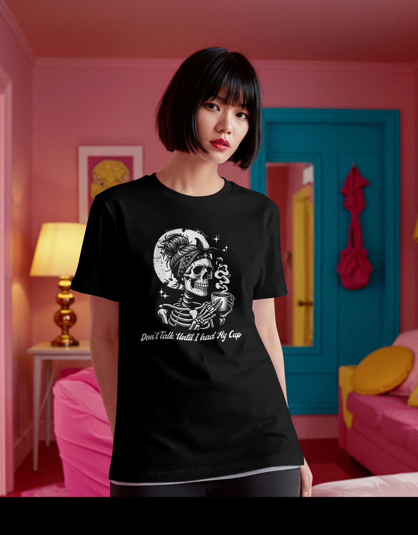 Person wearing a black t-shirt with a skeletal figure with bandana and skeleton hand holding a smoking cup, against a black background with moon and stars. The model is in a room with pink walls and colorful decor.