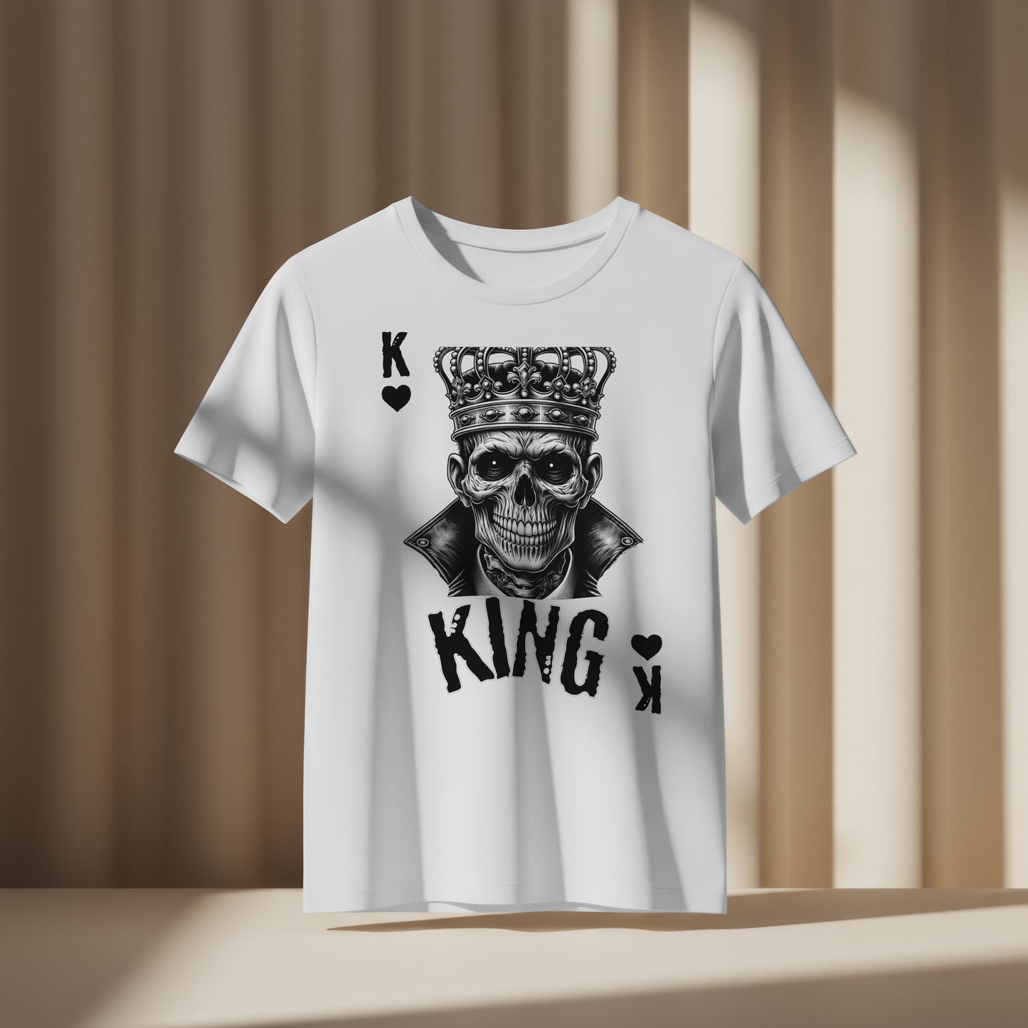White t-shirt with a skull wearing a crown with 'KING' text and playing card symbols on a white background, on a beige background
