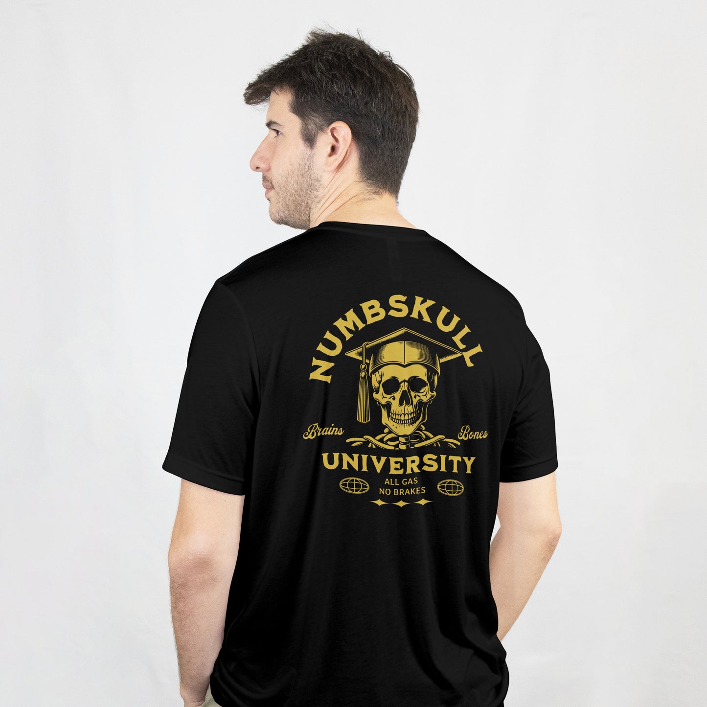 Man wearing a black t-shirt with gold skull with graduation cap and 'Numbskull University' text on a black background on the back of the t shirt.
