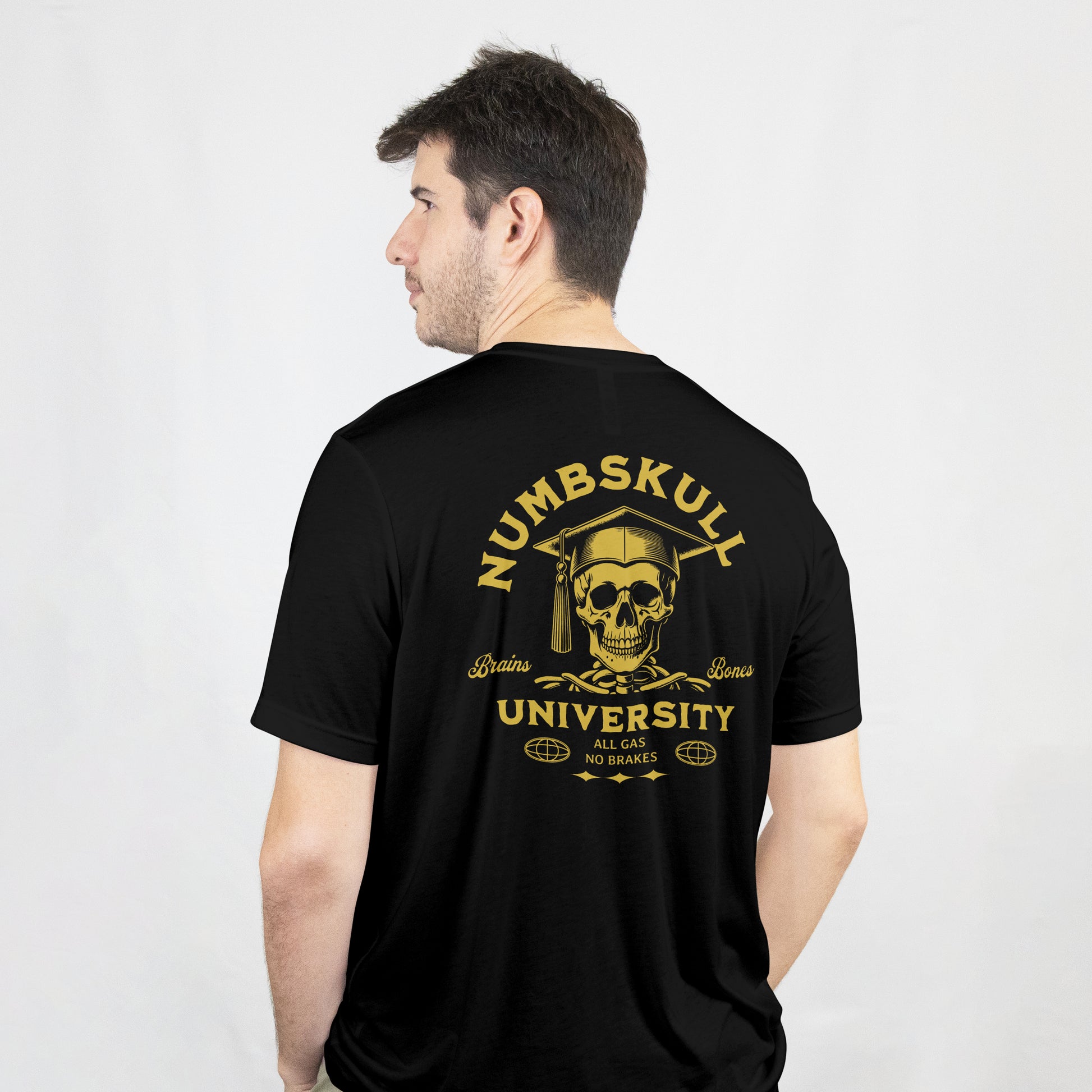 Man wearing a black t-shirt with gold skull with graduation cap and 'Numbskull University' text on a black background on the back of the t shirt.