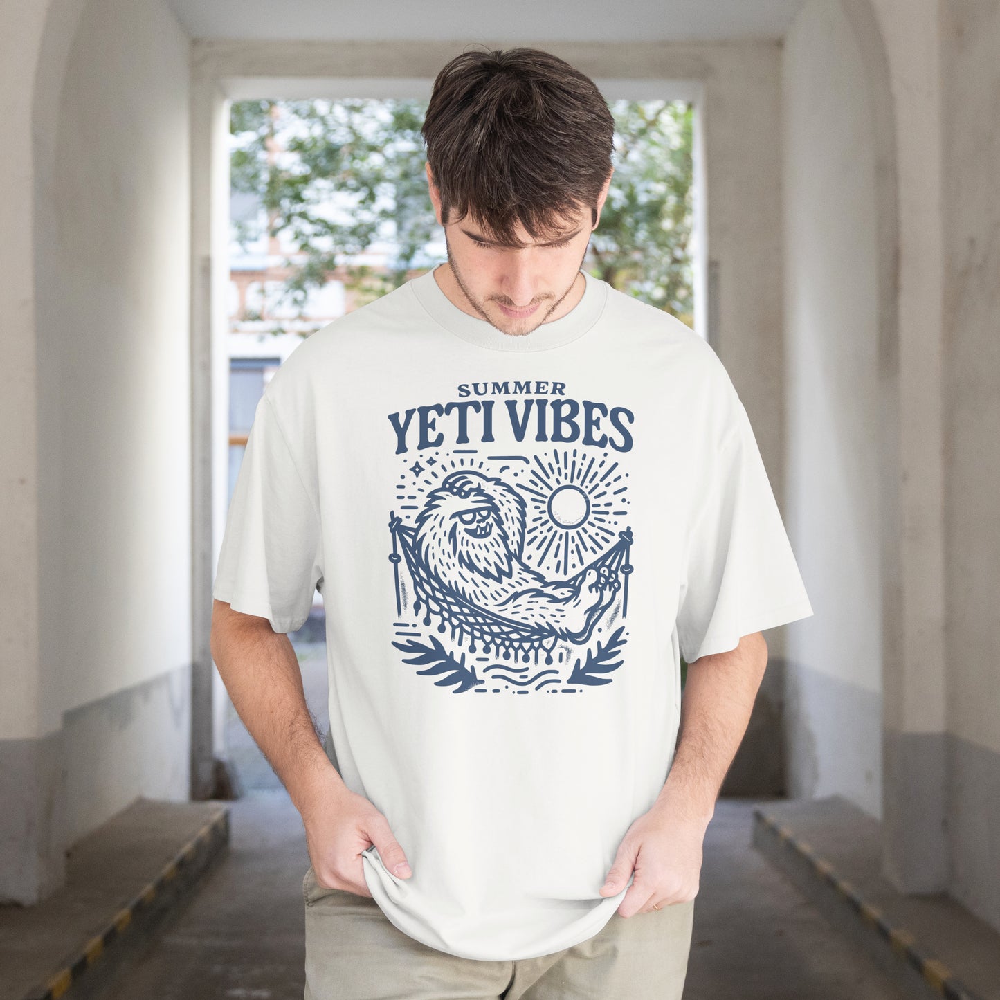 Person wearing a white t-shirt with 'YETI VIBES' design in a room with large windows.